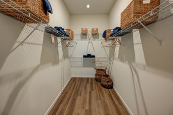 A walk-in closet with white walls and wooden floors.